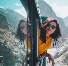 two women in sunglasses are looking out the window of a bus on a mountain road