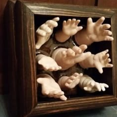 there are many small plastic hands in a wooden frame