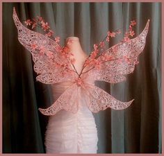 a mannequin with pink flowers on it's head and wings in the shape of an angel