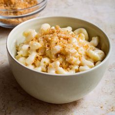 a white bowl filled with macaroni and cheese on top of a marble counter