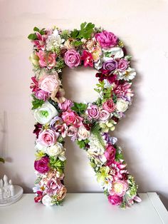 the letter r is made up of flowers and greenery on top of a dresser