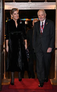 two people walking down a red carpeted hallway