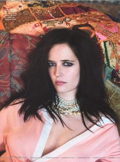 a woman laying on top of a bed wearing a pink shirt and choker necklace