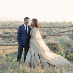 a bride and groom standing in front of a wooden fence