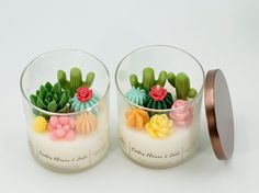 two glass vases filled with fake flowers and cactus plants on top of each other