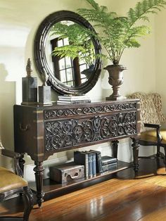 a mirror sitting on top of a wooden table next to a chair and a potted plant