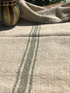 the sun is shining on a table cloth with a vase in the foreground and a towel draped over it