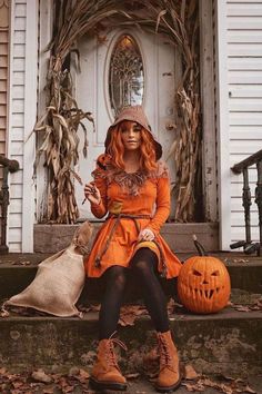 a woman in an orange dress and hat sitting on steps with pumpkins next to her