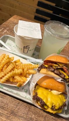 two cheeseburgers and fries are sitting on a tray next to a cup of soda