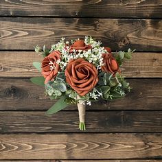 a bridal bouquet with orange roses and baby's breath on a wooden background