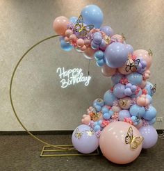 a balloon arch with balloons and butterflies on it