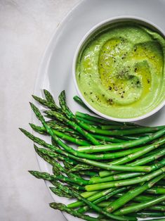 asparagus and dip in a bowl on a white plate next to green beans