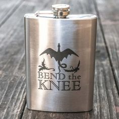 a stainless steel flask with the words bend the knee on it sitting on a wooden table