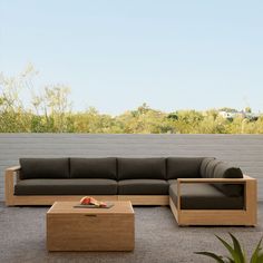 a couch and coffee table sitting in front of a brick wall with trees behind it