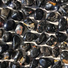 Small-sized, smooth, black, red, and yellow, Black Onyx tumbled pocket stones against a marbled background. Tumbled Crystals, Third Eye Opening, Colors Of Fire, Increase Intuition, Key Words, Raw Rose Quartz, Orange Crystals, Black Onyx Stone, White Crystals