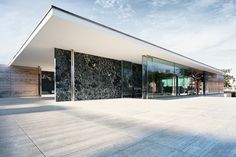 an empty building with glass walls and doors on the outside, against a blue sky