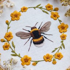 a close up of a bee on a white cloth with yellow flowers