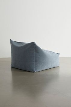 a blue bean bag sitting on top of a cement floor next to a white wall