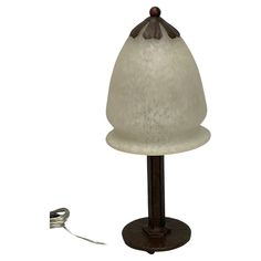 a lamp that is sitting on top of a wooden stand with a cord attached to it