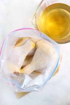 two raw chicken in plastic bags next to a bottle of oil