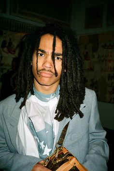 a man with dreadlocks and a tie holding a pair of scissors in his hands