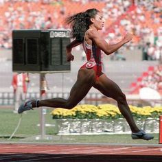 a woman running on a track in front of an audience