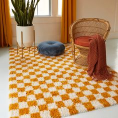 an orange and white checkered rug next to a chair with a pillow on it