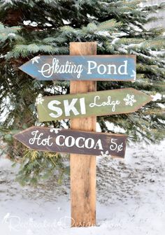 a wooden pole with several different signs on it in the snow next to a pine tree