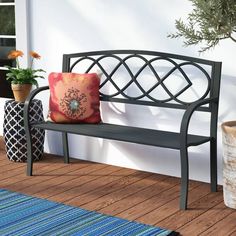 a black bench sitting on top of a wooden floor next to a potted plant