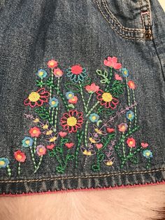 the back of someone's jean jacket with embroidered flowers on it and a furry tail