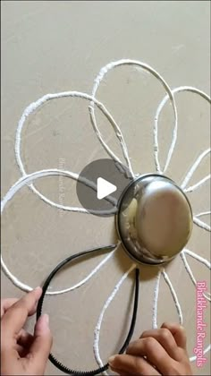 someone is painting a flower on the wall with white paint and some black wires attached to it