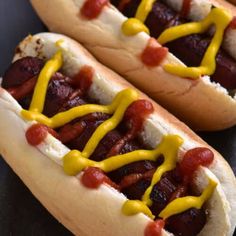 two hotdogs with mustard and ketchup on them sitting next to each other