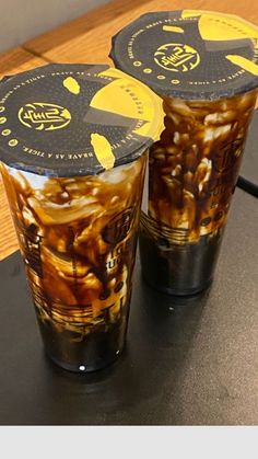 two plastic cups filled with food sitting on top of a black table next to each other