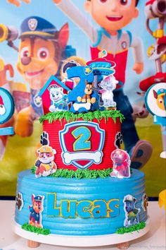 the birthday cake is decorated with paw patrol characters on it's tiered red and blue icing