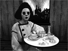 a person in a skeleton mask sitting at a table with food and drinks on it