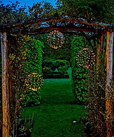 an archway with lights in the middle of it and vines growing on either side to create a trellis