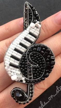 a black and white beaded brooch with a musical note on it's side