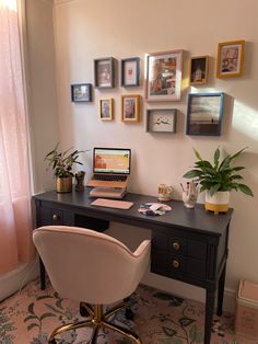 a desk with a laptop on top of it next to a potted plant and pictures