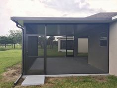 an enclosed patio with sliding glass doors on the side and grass in front of it