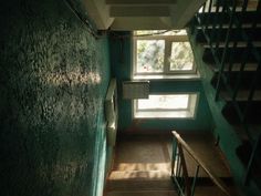 the stairs lead up to an open window in a green room with blue painted walls