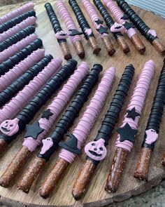 there are many different types of candy sticks on the wooden board with black and pink icing