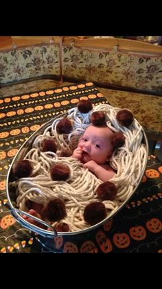 a baby laying in a bowl filled with noodles and pom - pompons