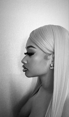 a woman with long blonde hair and earrings on her head is standing in front of a white wall