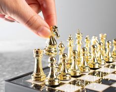 a person is playing chess with gold pieces