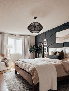 a bedroom with a bed, chair and window in the corner that has curtains on both sides