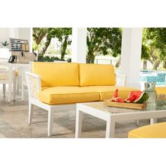 a yellow couch sitting on top of a patio next to a white table and chairs