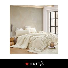 a bed with white sheets and pillows in a room next to a window that reads macy's