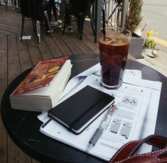 a table topped with books next to a glass of liquid and a book bag on top of it