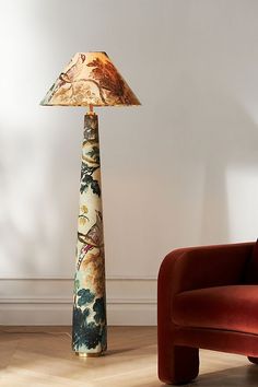 a lamp sitting on top of a wooden floor next to a red chair