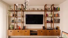 an entertainment center with bookshelves, shelves and a flat screen tv mounted on the wall